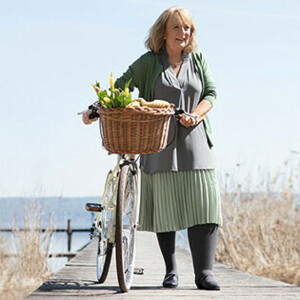Eine Dame schiebt ein Fahrrad auf einem Steg