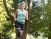 Eine ältere Frau mit Sportklamotten befindet sich im Grünen beim Joggen