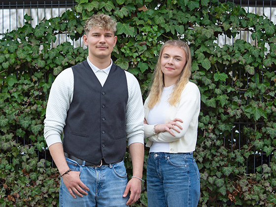 Azubisprecher Silvio und Azubisprecherin Luisa Der Azubisprecher Silvio und die Azubisprecherin Luisa stehen vor einer mit Efeu abgedeckten Wand