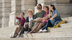 Friends sit on a staircase. Some of them are wearing compression stockings.