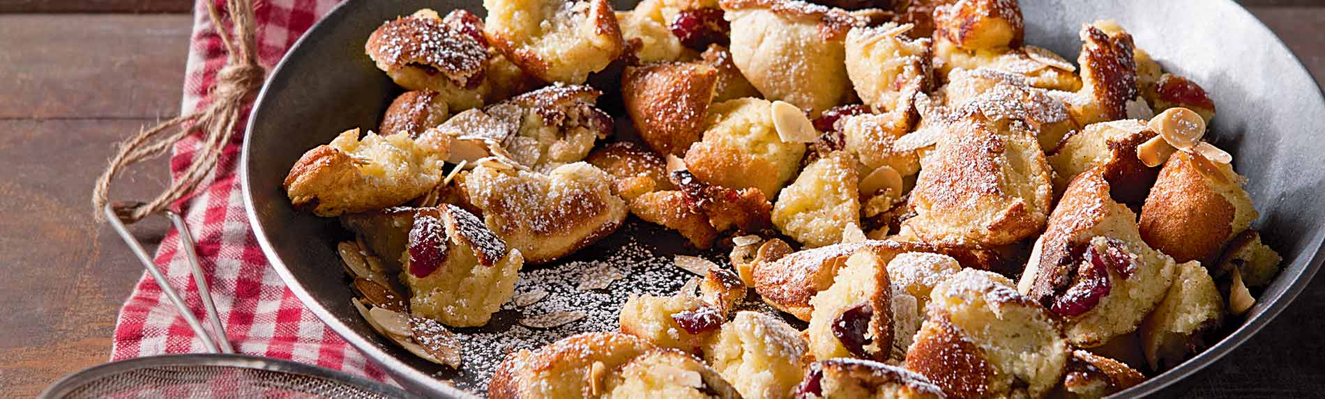 Kaiserschmarrn mit Mandeln und Zwetschgen-Kompott Kaiserschmarrn mit Mandeln und Zwetschgen-Kompott in der Pfanne