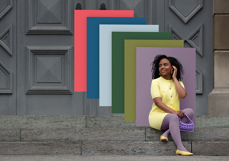 Een vrouw zit op stenen treden voor een poort. Ze draagt een lichtgele tweedelige outfit met een paarse compressiekous. Achter haar zie je kleurvlakken in de trendkleuren.