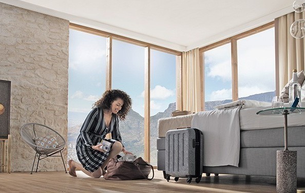 Frau packt Reisetasche im Hotelzimmer aus