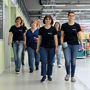 Sieben Frauen mit schwarzen Juzo T-Shirts laufen durch unsere Produktion