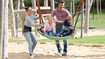 A family on the playground. Children in the monkey swing. The mother is wearing a back support