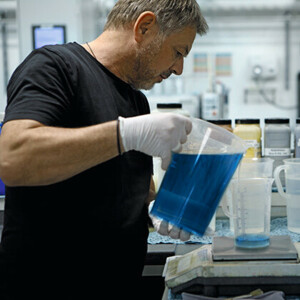 Mann in der Färberei hat ein Gefäß mit blauer Farbe in der Hand