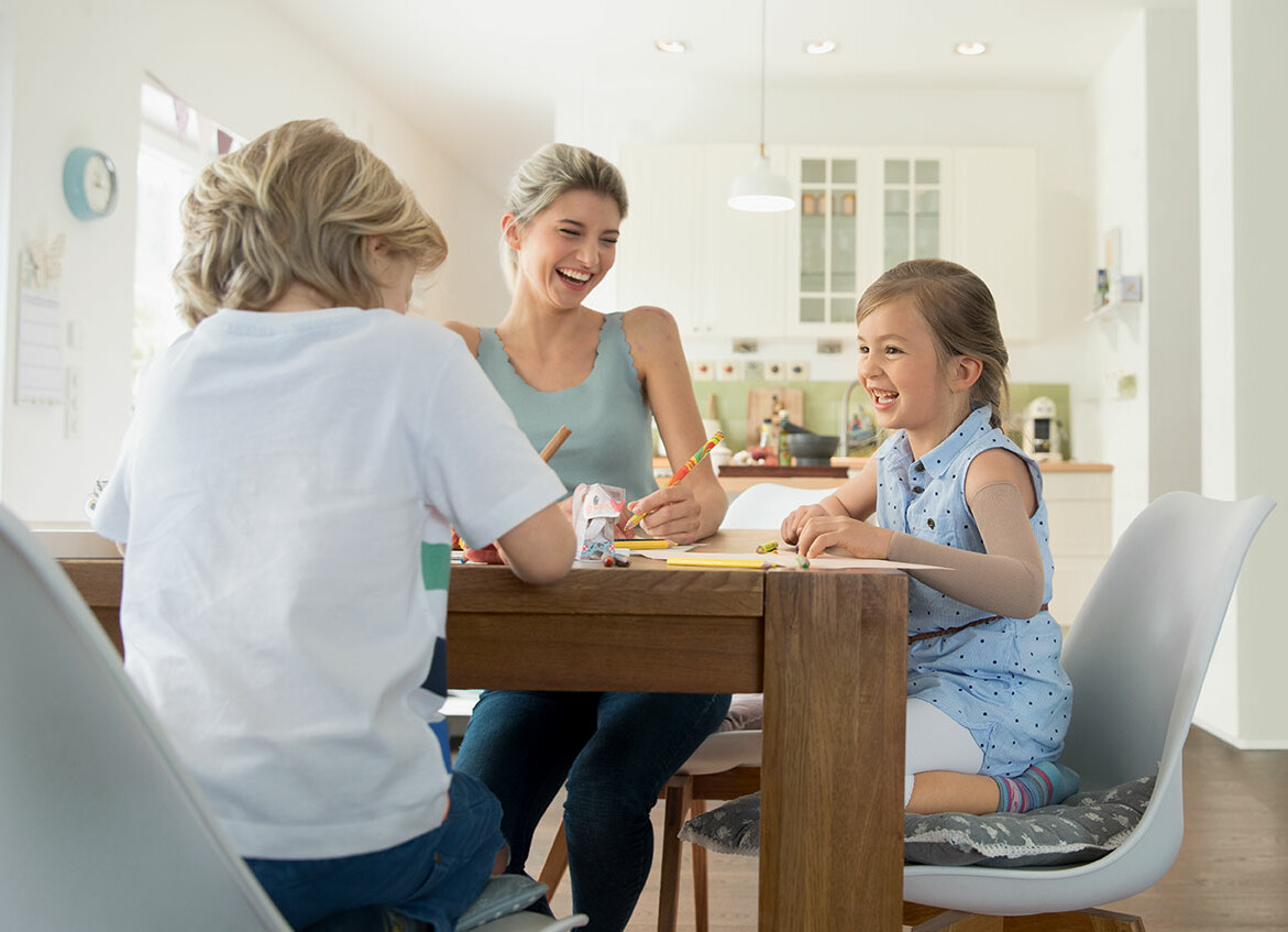 Narbenmanagment Mutter und Kind sitzen zusammen am Esstisch und haben Spaß