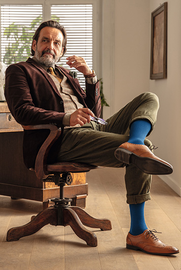 11. Lifestyle Bild Juzo Adventure Mann trägt den Juzo Adventure in Blaubeere und sitzt an seinem Schreibtisch