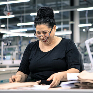 Frau mit schwarzen Haaren schneidet mit einem Lächeln im Gesicht ein Produkt zurück