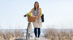 Woman with compression stockings is pushing her bike.