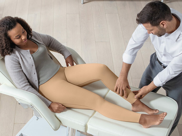 Ein Arzt überprüft bei einer Patientin den Sitz der Juzo Comprima Leggins