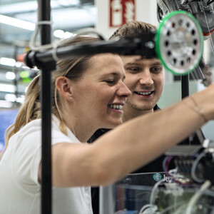 Eine Frau und ein Mann betrachten eine Strickmaschine