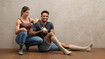A man and a woman are sitting on the floor. Both are wearing compression stockings on their lower legs. The man is holding a small bunny in his hands