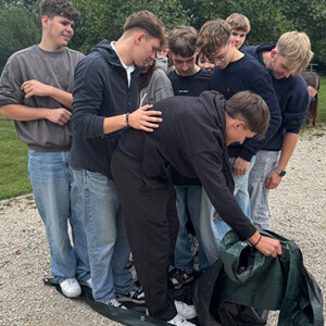 Eine Gruppe von Azubis bei einer Teambuildingaufgabe mit einer Plane