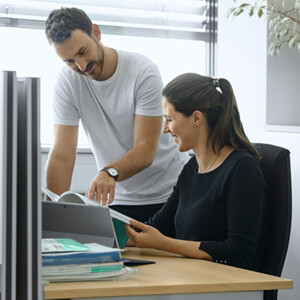 Ein Mann und eine Frau betrachten zusammen an einem Arbeitsplatz eine Broschüre