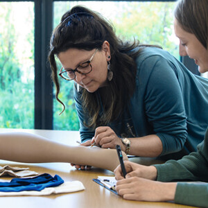Zwei Mitarbeiterinnen überprüfen eine Strumpf an einem Dekobein