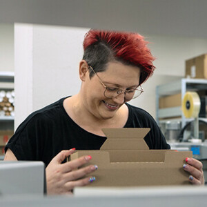 Mitarbeiterin im Logistikzentrum faltet einen Karton